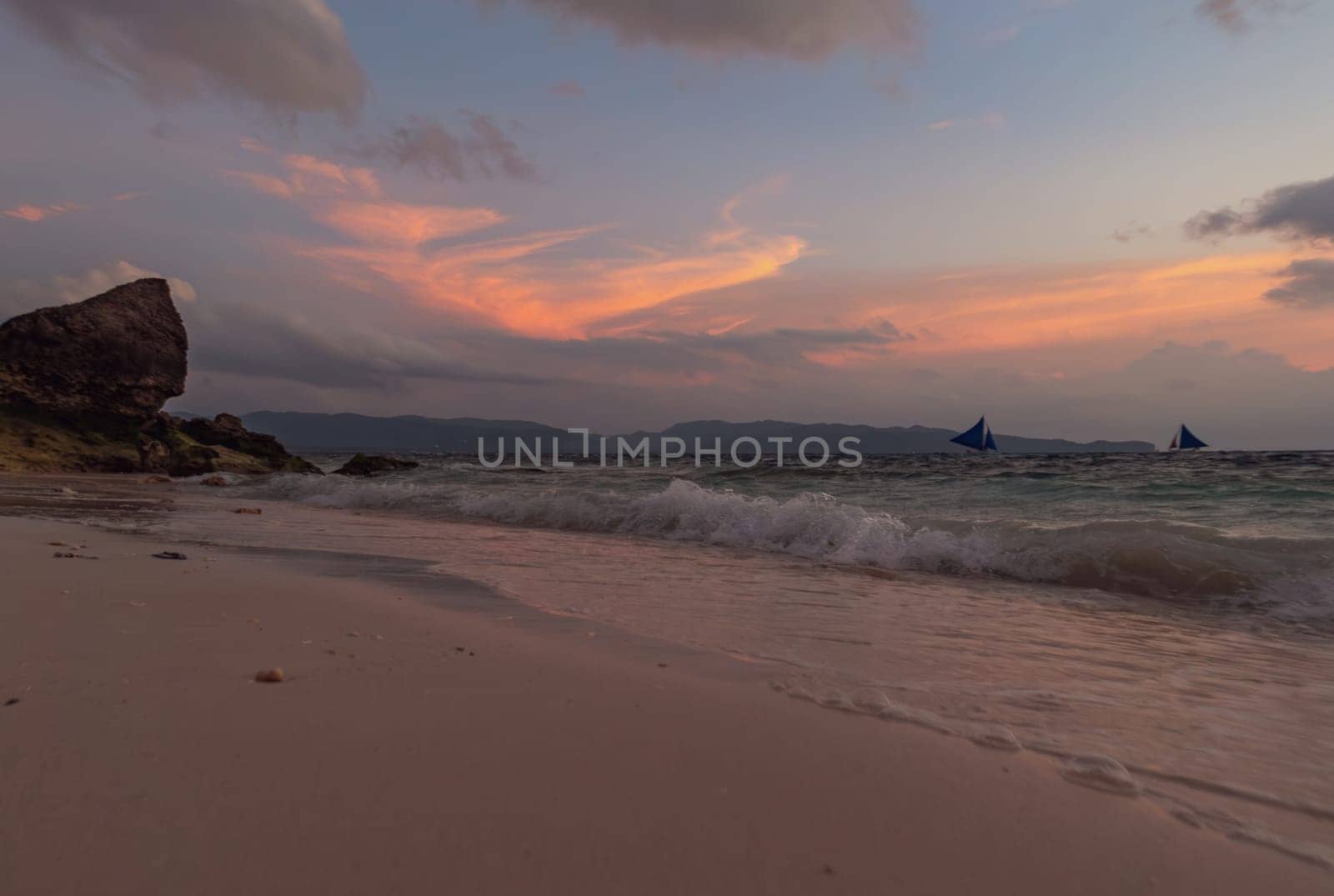 Calm evening on a sandy beach with boats sailing in the distance. Boracay, Philippines. by Busker