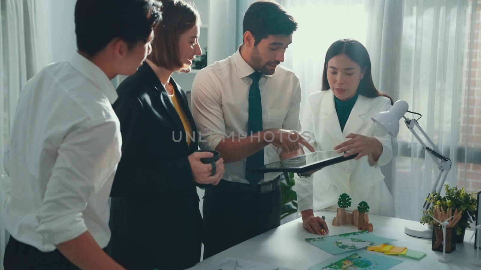 Professional smart business team discussing about using clean energy and sustainable investment at meeting table with wind mill, document with environmental graph and wooden house model. Alimentation.