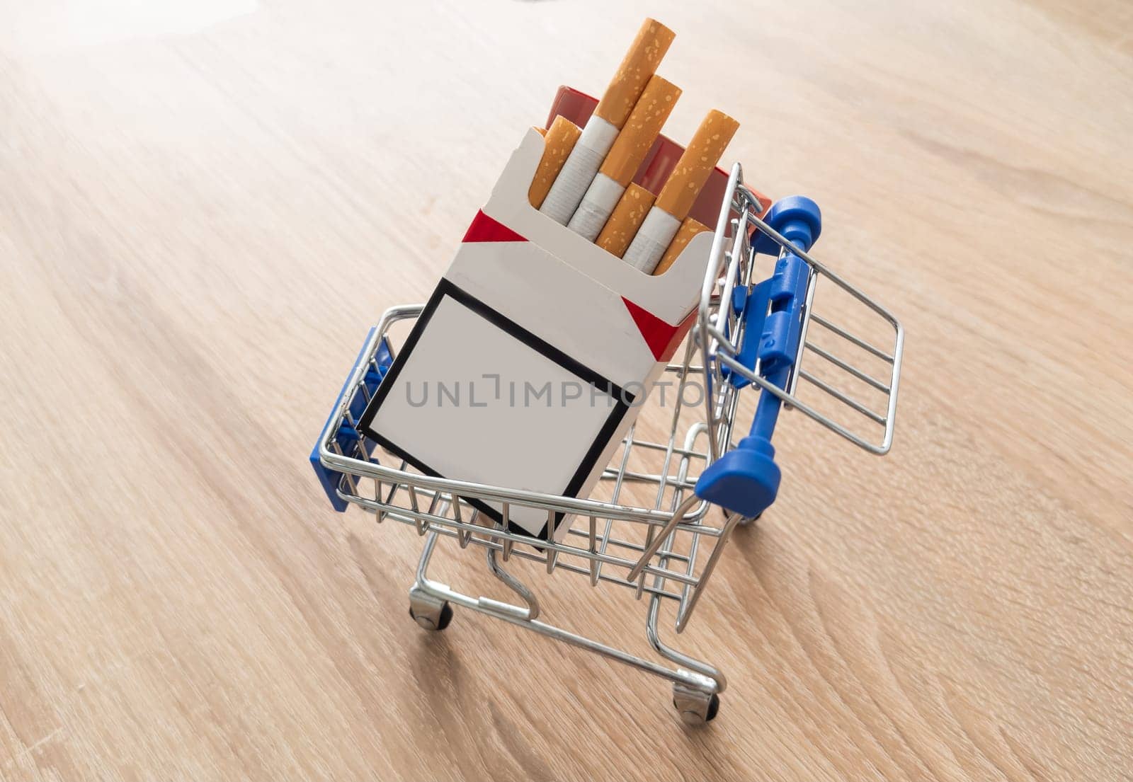 Cigarettes in shopping cart on wooden table on dark background. High quality photo