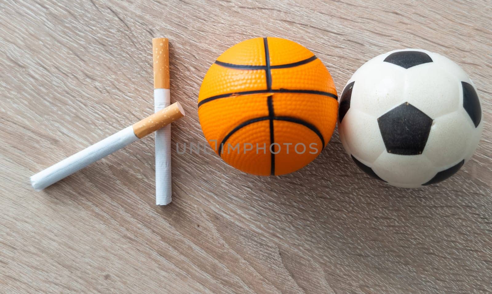 Smoking or sports. Sport ball and pack of cigarettes on table background. Top view. High quality photo