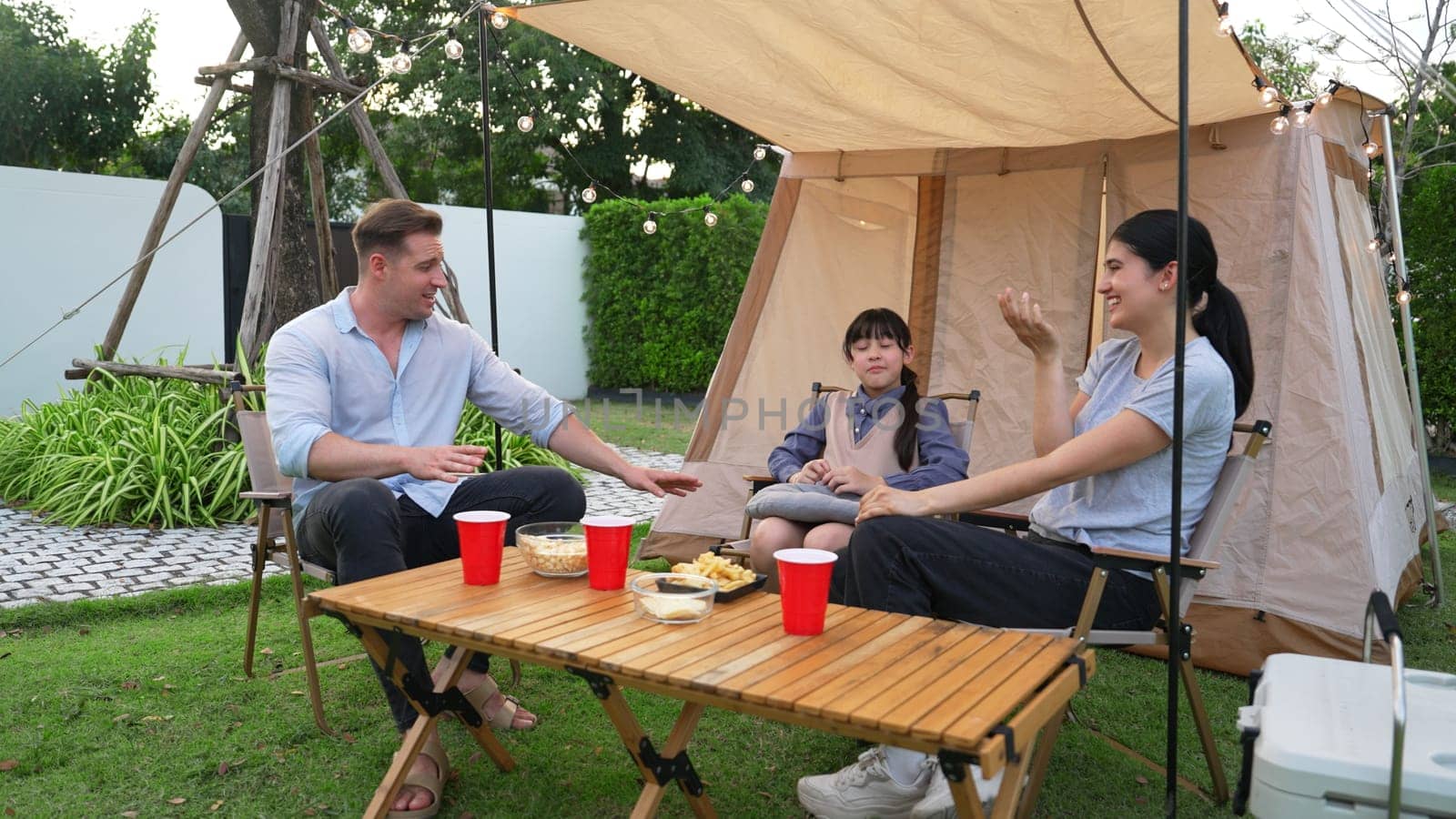 Family all together sit at camp in garden with tasty snack. Lovely parent use outdoor camping activity as way to communicate and spending time with young generation cross generation gap. Divergence.