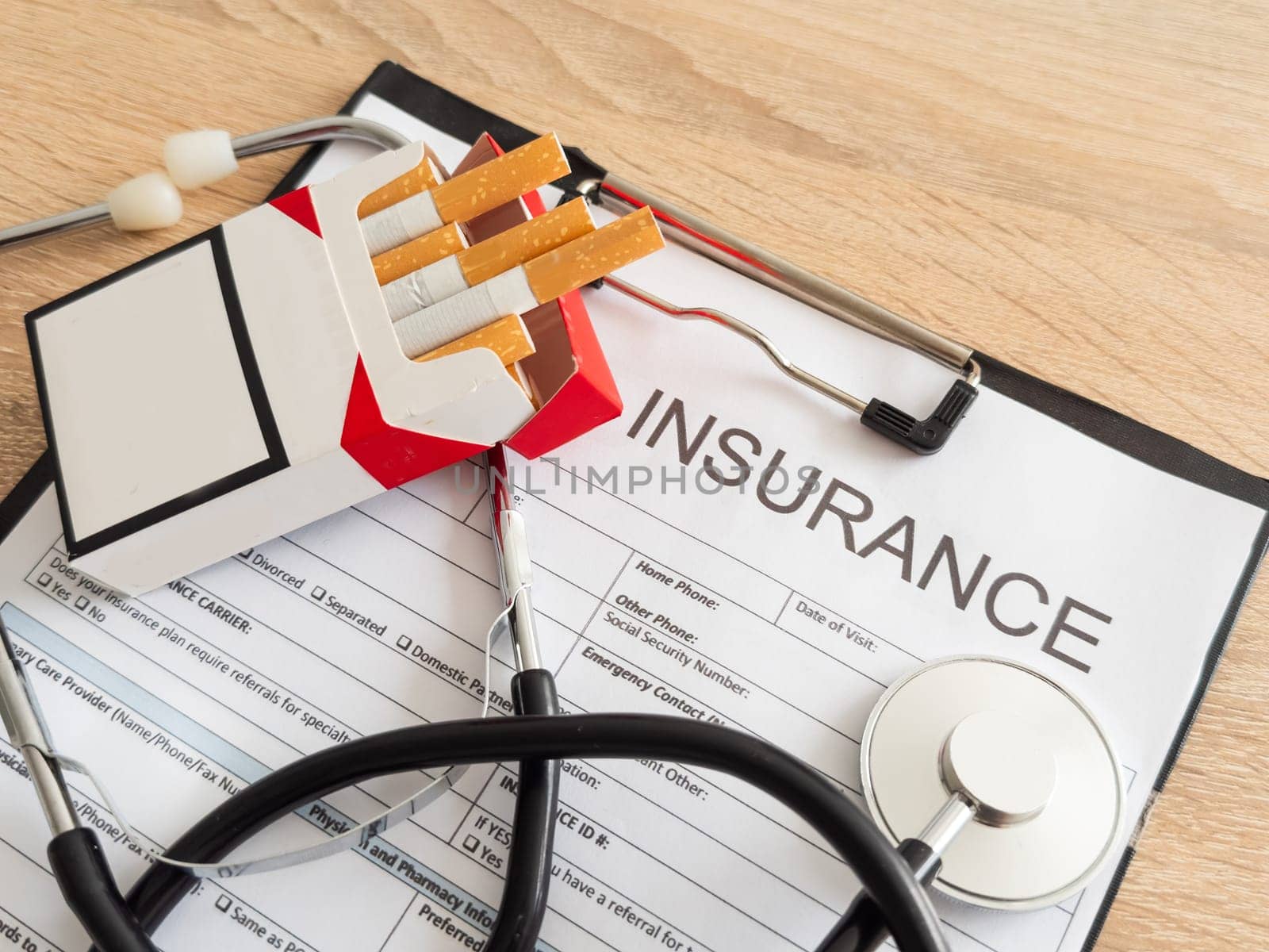 Cigarettes and stethoscope on insurance documents. High quality photo