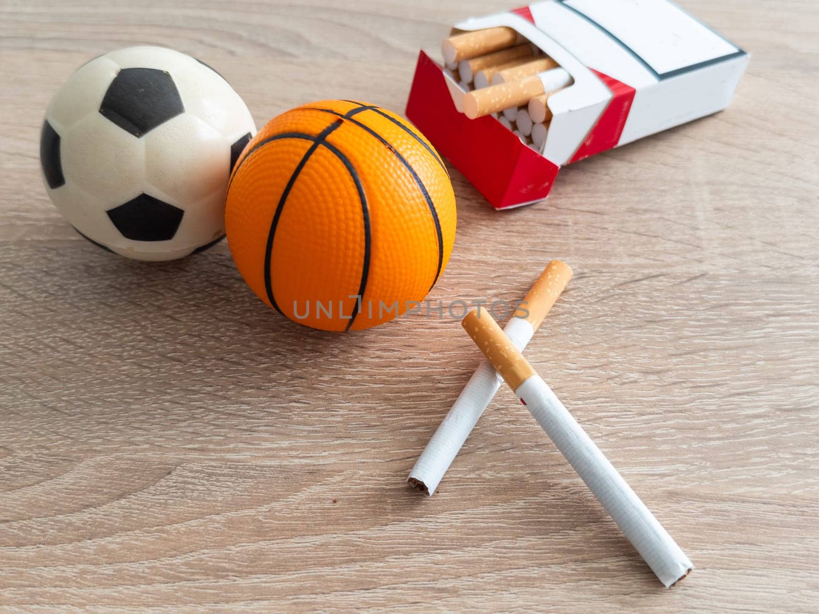 Smoking or sports. Sport ball and pack of cigarettes on table background. Top view. High quality photo