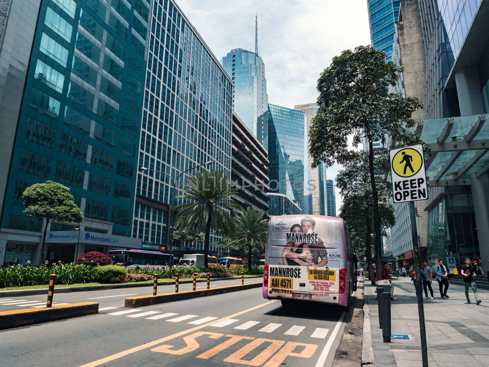 In the heart of Makati City, a bustling urban area features high-rise buildings and a public bus on a busy street promoting an event.