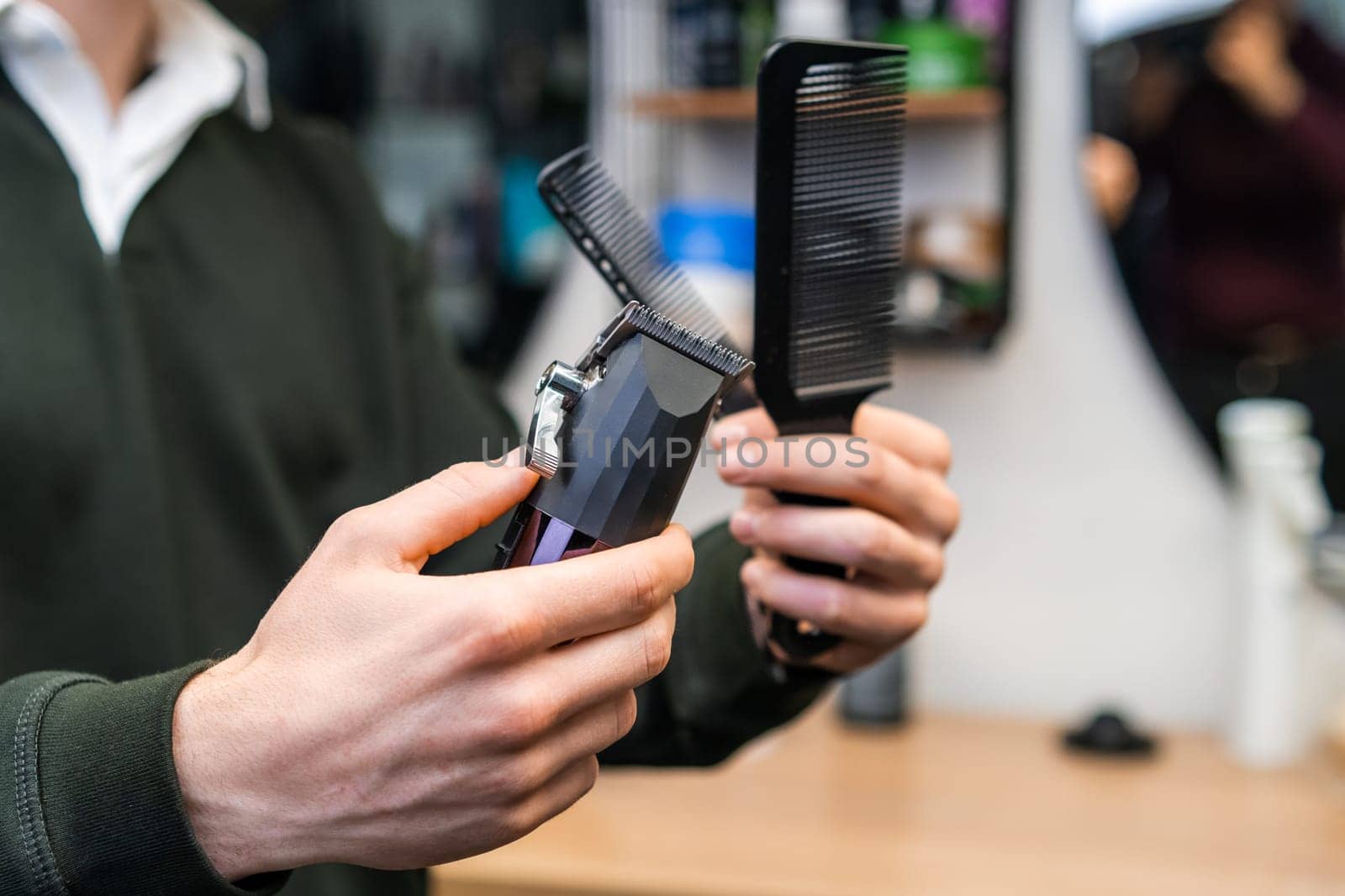 Barber holding combs and trimmer in the barbershop.
