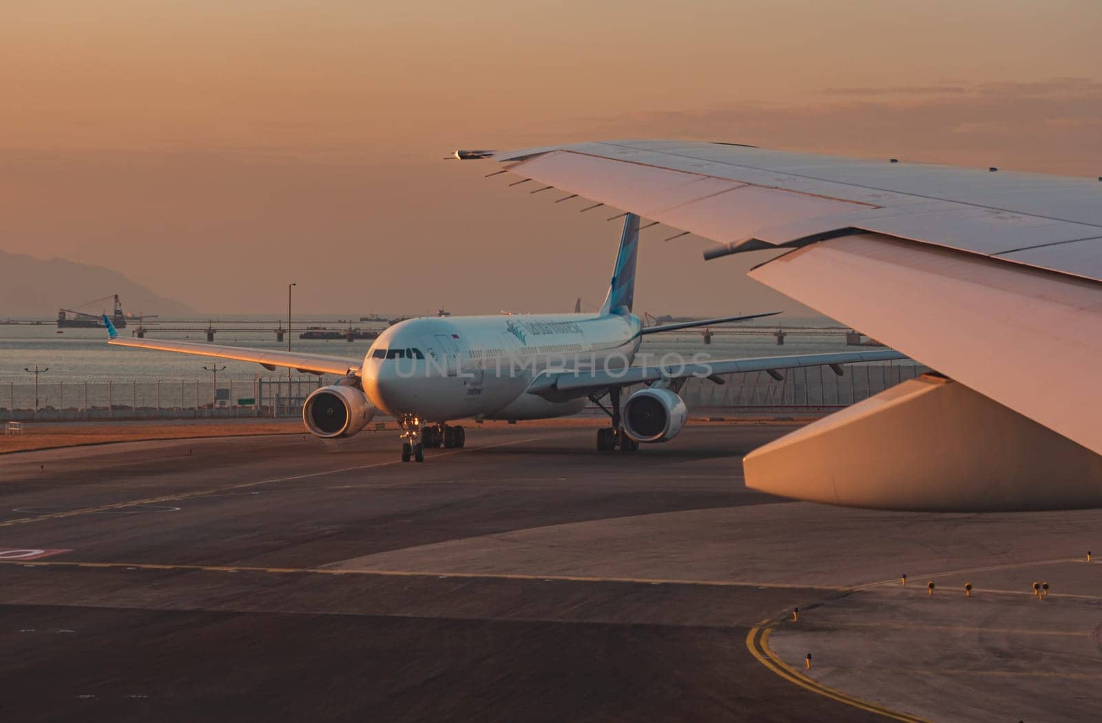 Hong Kong, China - January 28, 2019: Airplane taxiing on tarmac during sunset at Hong Kong international airport by Busker