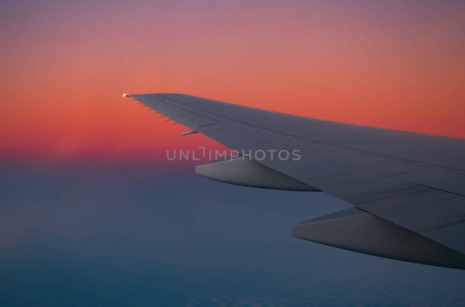 Airplane wing in flight during sunset with vibrant sky