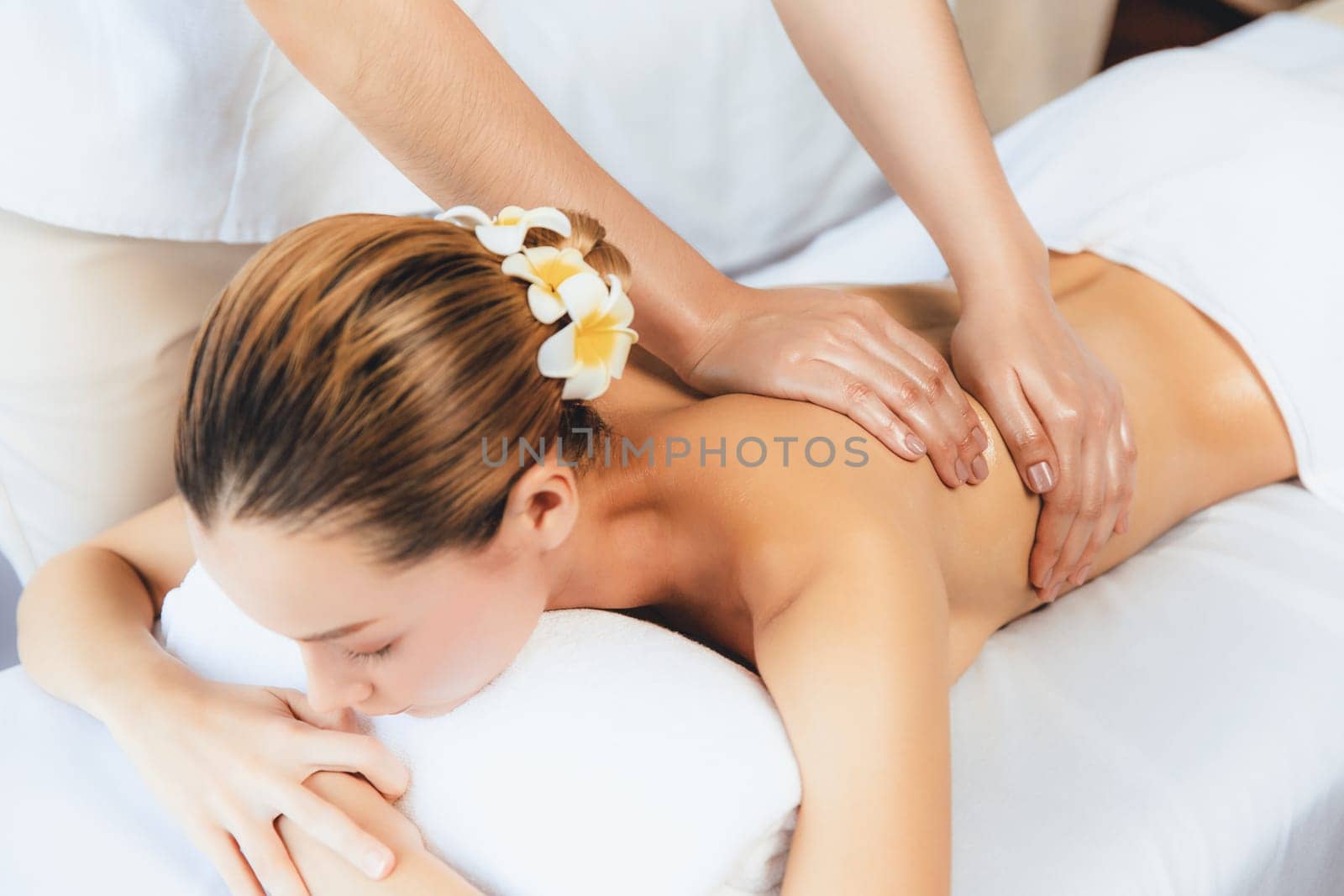 Caucasian woman customer enjoying relaxing anti-stress spa massage and pampering with beauty skin recreation leisure in day light ambient salon spa at luxury resort or hotel. Quiescent