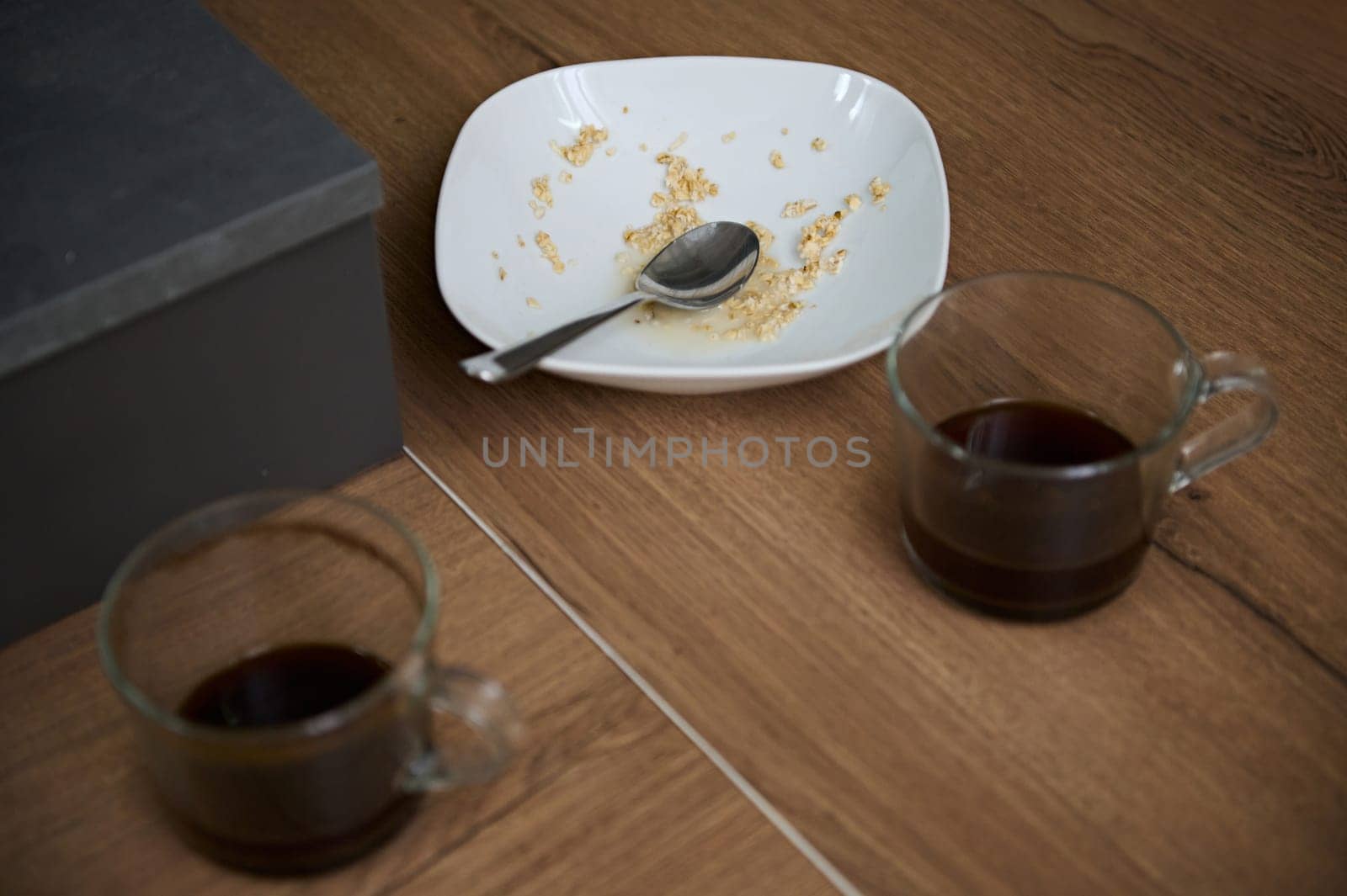 Overhead view of left over of breakfast in white ceramic bowl and two glass cups of unfinished coffee on the table