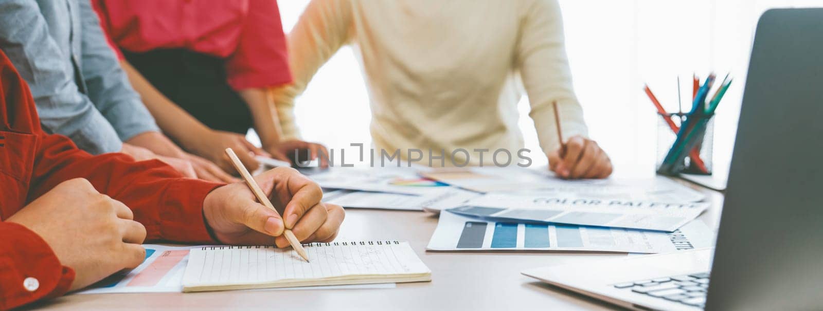 A cropped image of skilled interior designer team discussing about color using while project manager taking a note. Creative working and design concept. Closeup. Focus on hand. Variegated