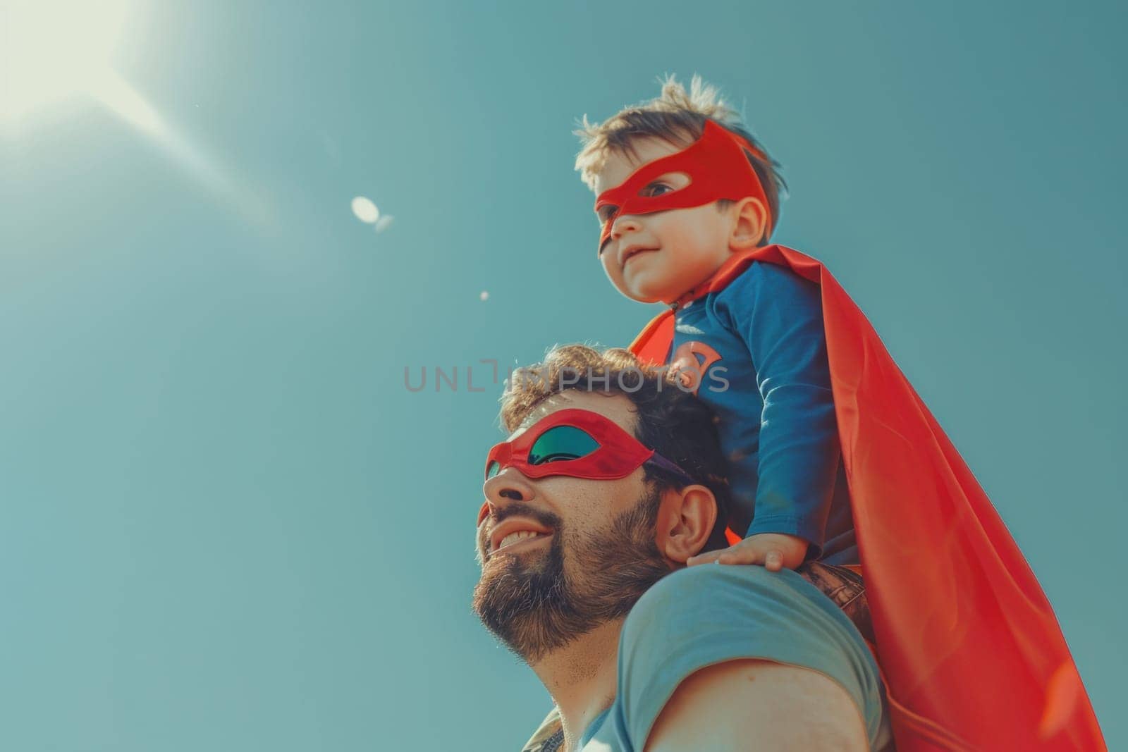 Father and son superheroes enjoying a sunny day in front of blue sky, showing strength and unity