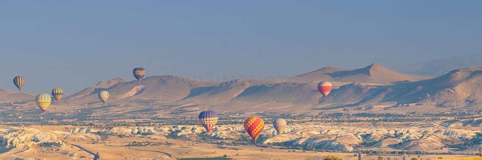 Banner of Cappadocia Turkey 08.01.2021 Large colored hot air balloons fly against the backdrop of mountain landscapes at sunrise early in the morning. soft focus