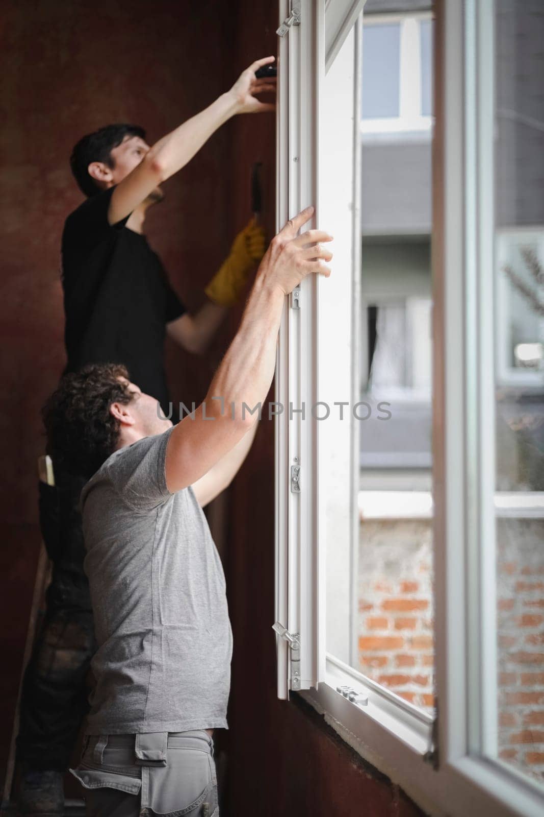Young people install a window frame. by Nataliya
