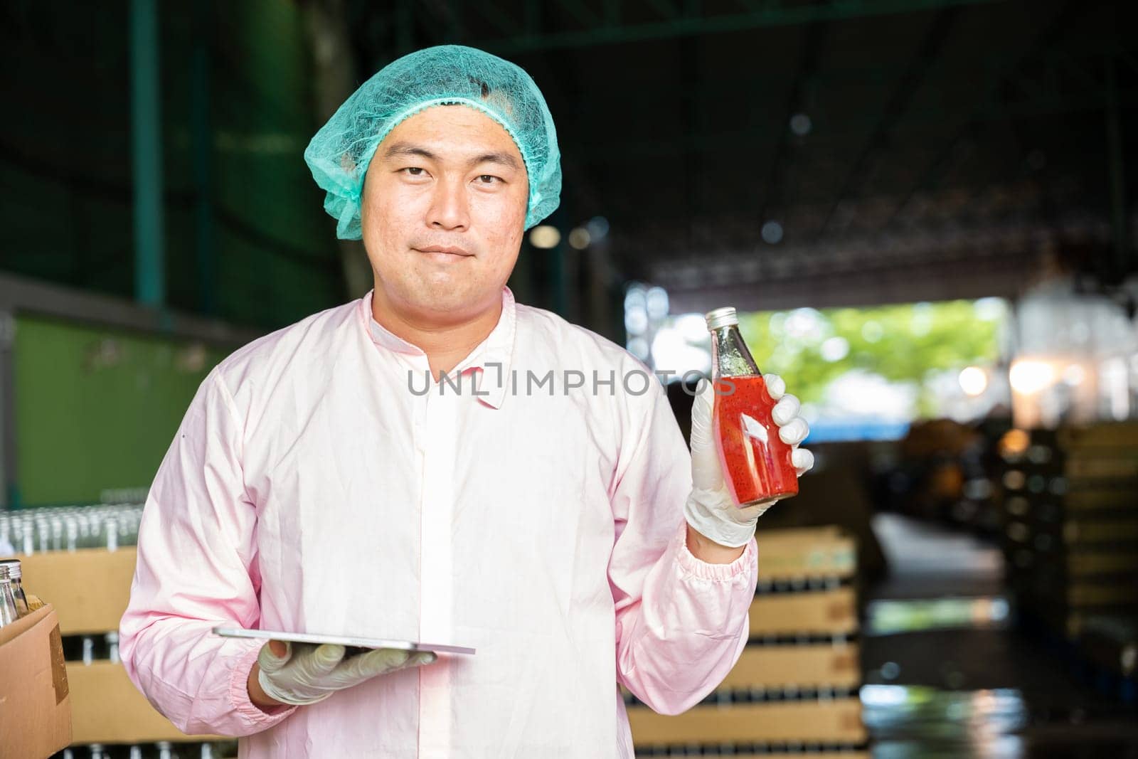 Inspector ensures bottle quality on conveyor belt at beverage factory before shipment. Colleague and engineer discuss inspection details on tablet focusing on efficient manufacturing.