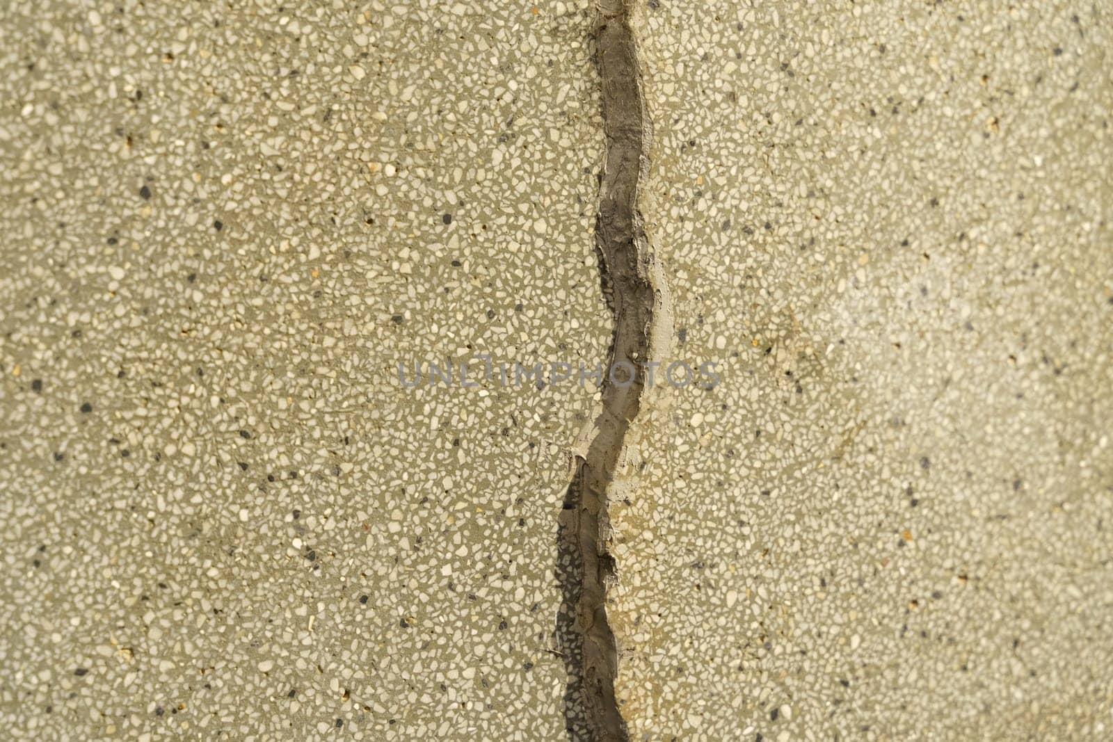 A close-up view of a cracked concrete wall, showcasing the texture and abstraction of the stone surface.