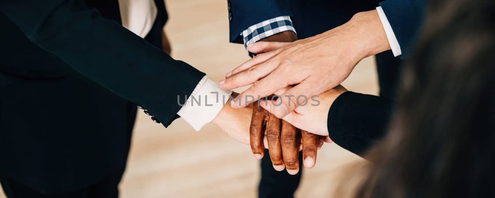 An above view of a diverse business group holding hands in a circle. This act of teamwork and togetherness in the modern office exemplifies cooperation, communication, and a sense of community.