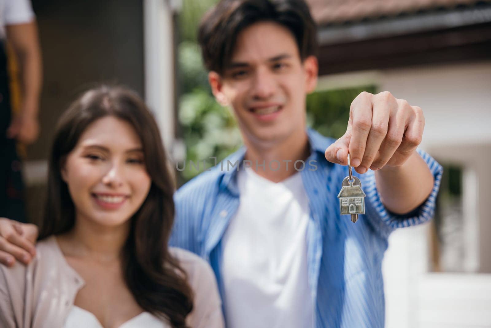 A couple happily displays keys carrying a mattress into their new home marking a triumphant relocation. The scene is filled with happiness. Moving Day Concept by Sorapop