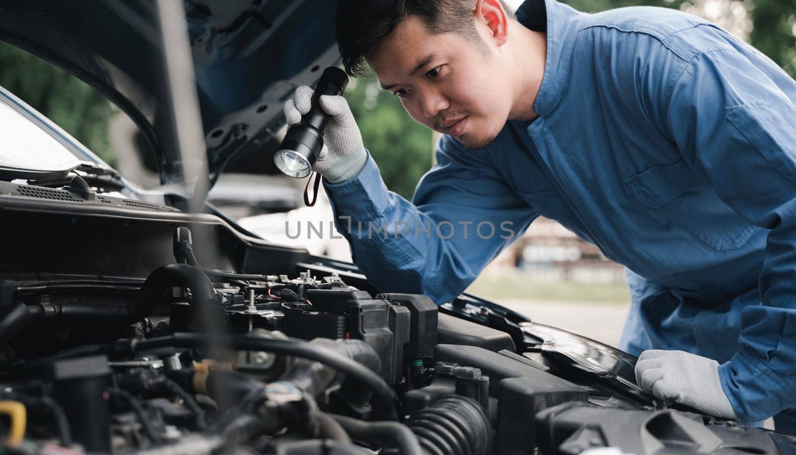 Man mechanic with lamp check a car. by Sorapop