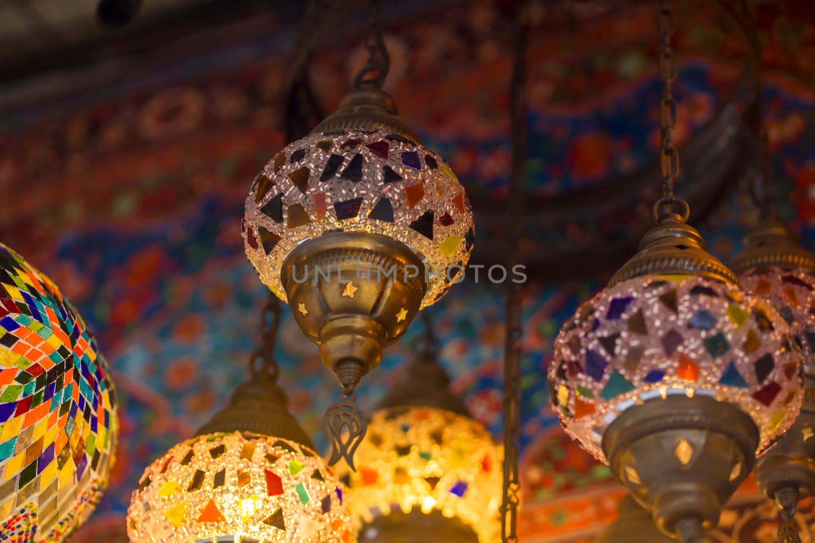 Middle Eastern lambas of different colors and sizes are hanging in the bazaar. Bright traditional Arabic and Turkish lanterns made of metal and glass, inlaid with mosaic details of different colors.