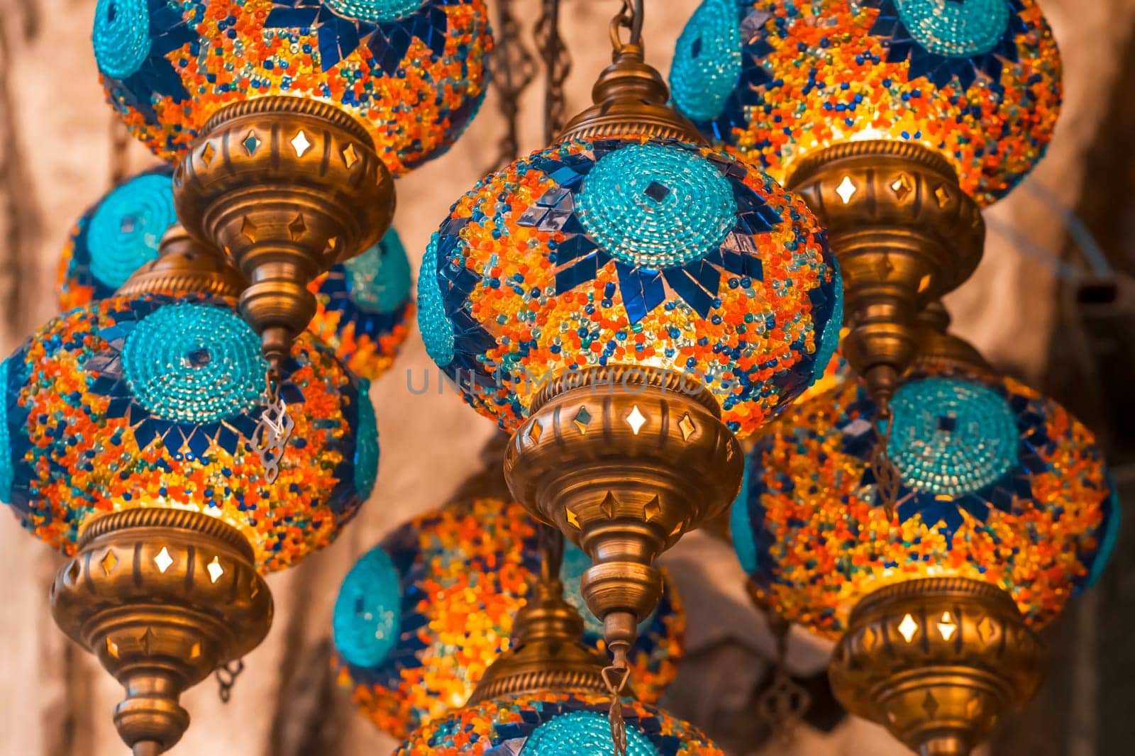 Middle Eastern lambas of different colors and sizes are hanging in the bazaar. Bright traditional Arabic and Turkish lanterns made of metal and glass, inlaid with mosaic details of different colors.