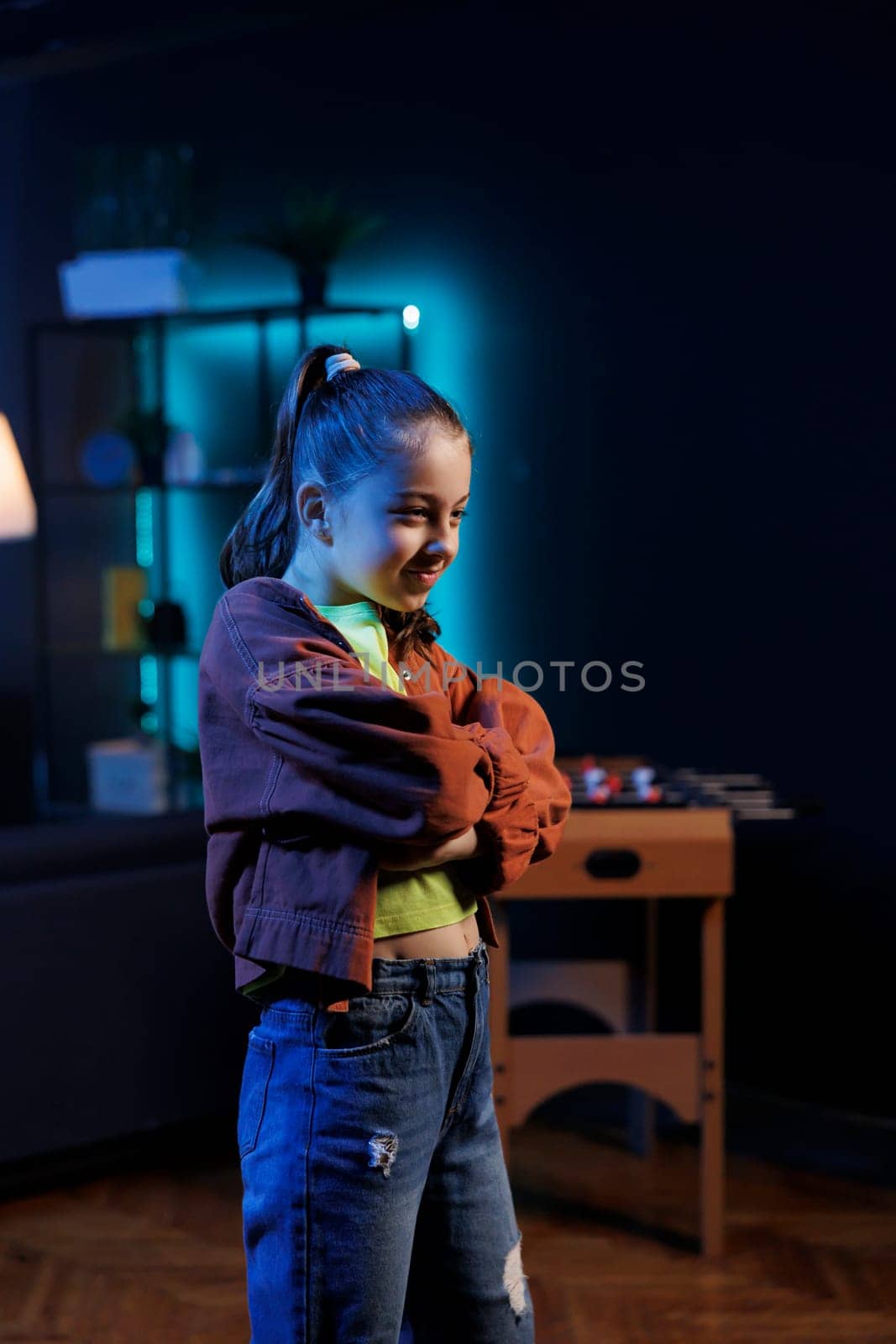 Young child in dimly lit studio doing viral dance for social media platforms while listening to popular hit song. Cute gen Z girl recording dancing video for her internet fans on latest viral music