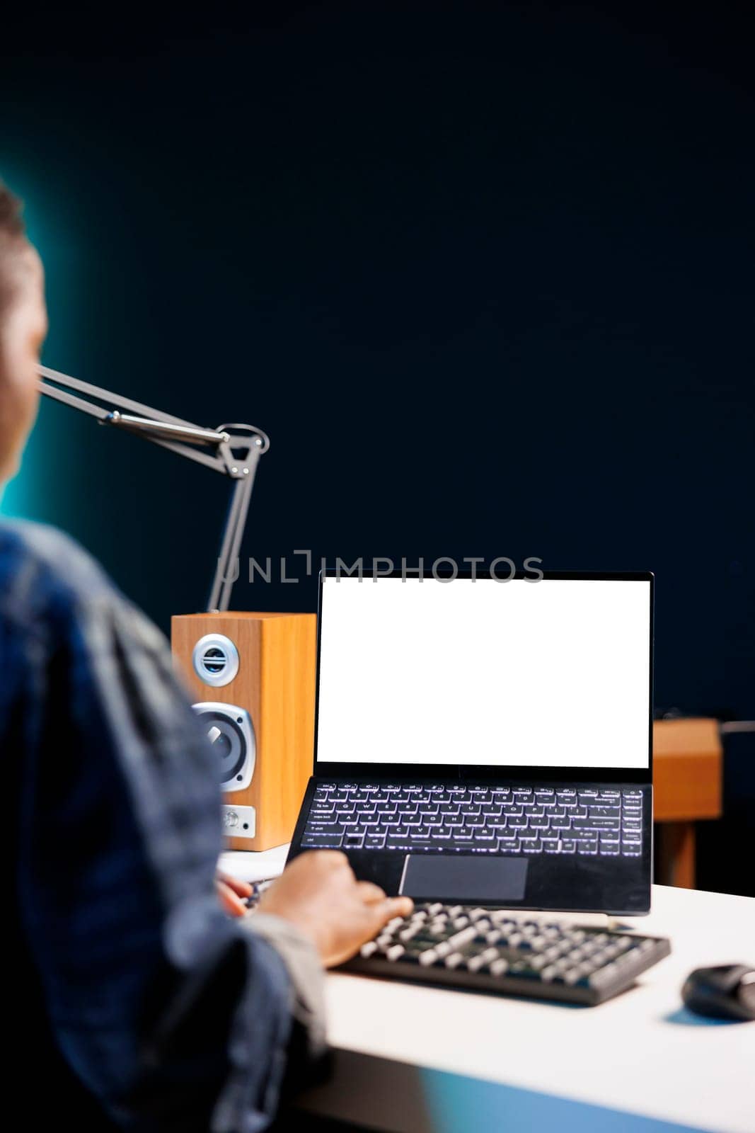 Black woman working from home at a desk with wireless computer displaying an isolated white screen. African american person using digital laptop showing blank chromakey mockup template.