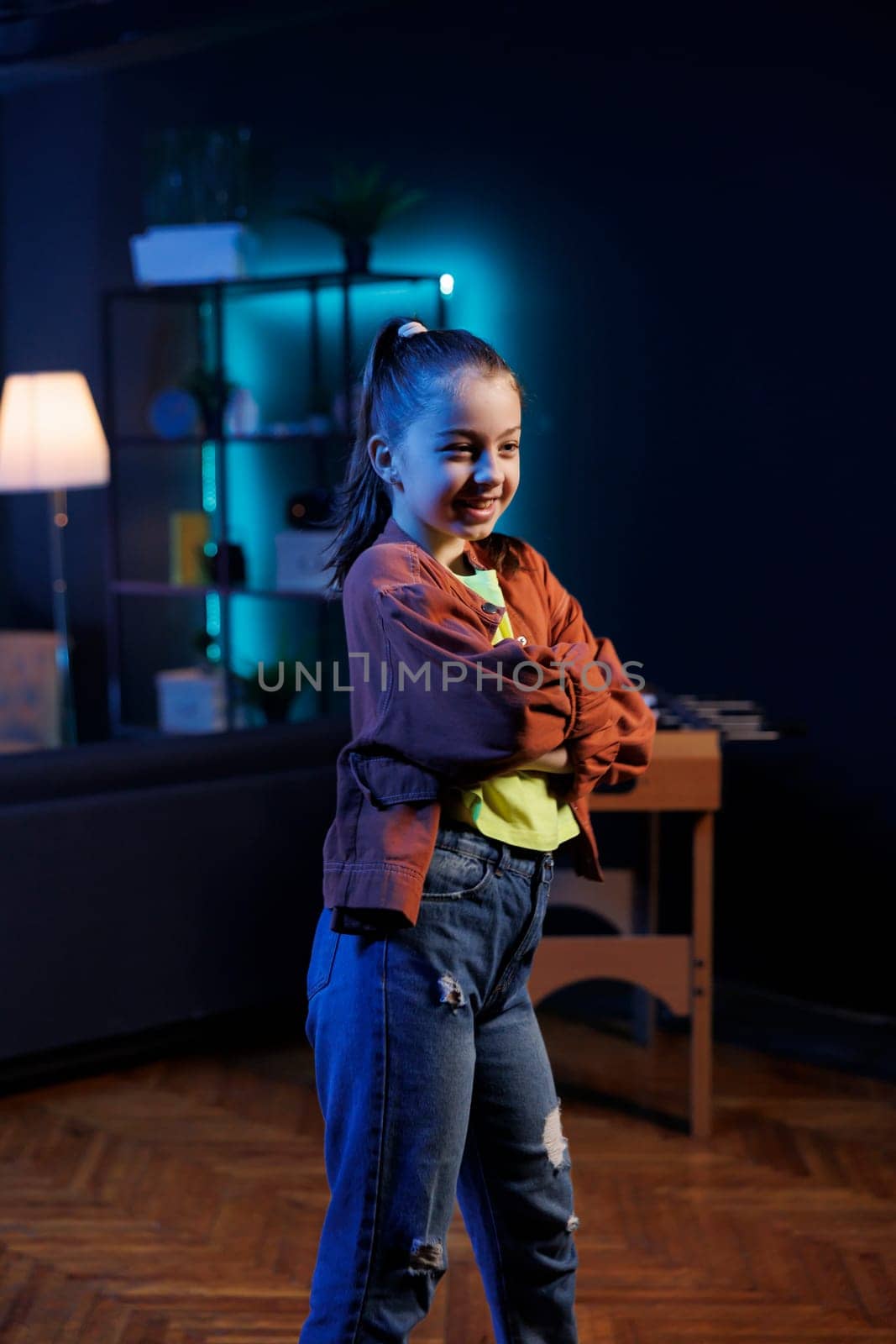 Smiling kid joins viral dance craze, using professional camera to record family friendly video for children. Little girl does latest trending internet dancing challenge in dimly lit room