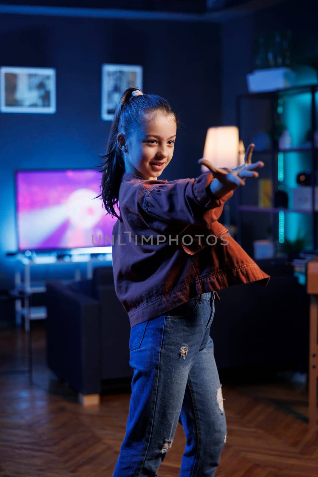 Young child doing viral dance for social media platforms while listening to popular hit song. Small girl recording dancing video for her internet fans on latest viral music