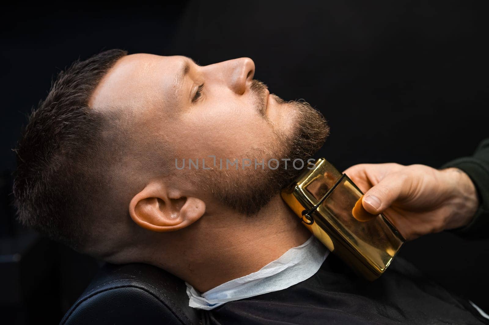 Hairdresser cutting bread with trimmer for man in barbershop