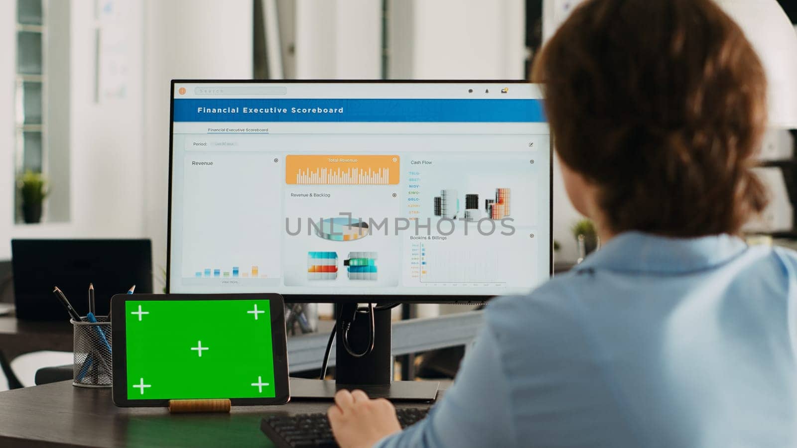 Office worker checks greenscreen display on tablet, working on business operations with isolated copyspace template and analyzing data on computer at desk. Having gadget with mockup.