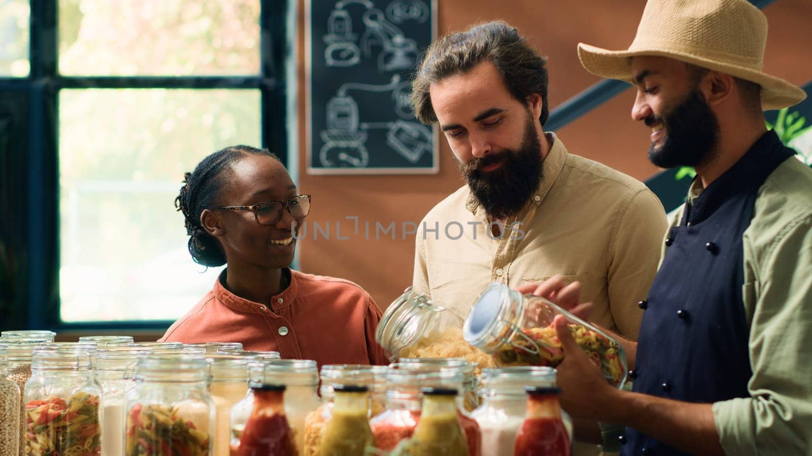 Vendor showing eco bulk products to couple at local organic supermarket, sharing his pasta bolognese recipe with special homemade sauce. Excellent customer service at zero waste store.