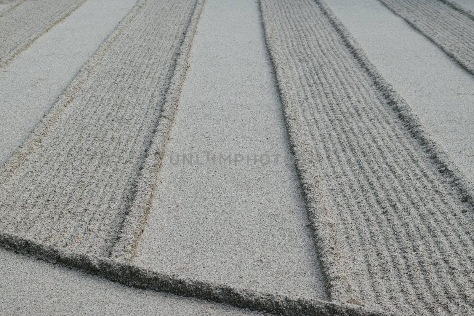 Close-up of a zen garden with meticulously raked sand creating parallel lines and patterns.