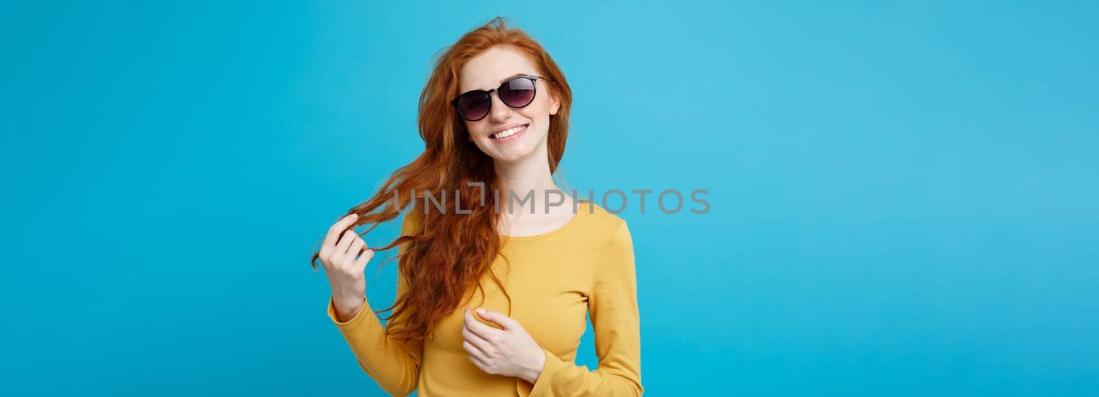 Travel concept - Close up Portrait young beautiful attractive ginger red hair girl with trendy sunglass smiling. Blue Pastel Background. Copy space. by Benzoix