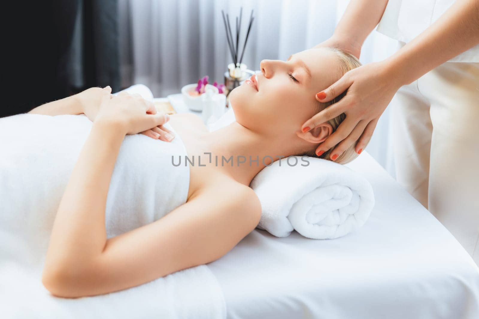 Caucasian woman enjoying relaxing anti-stress head massage and pampering facial beauty skin recreation leisure in dayspa modern light ambient at luxury resort or hotel spa salon. Quiescent