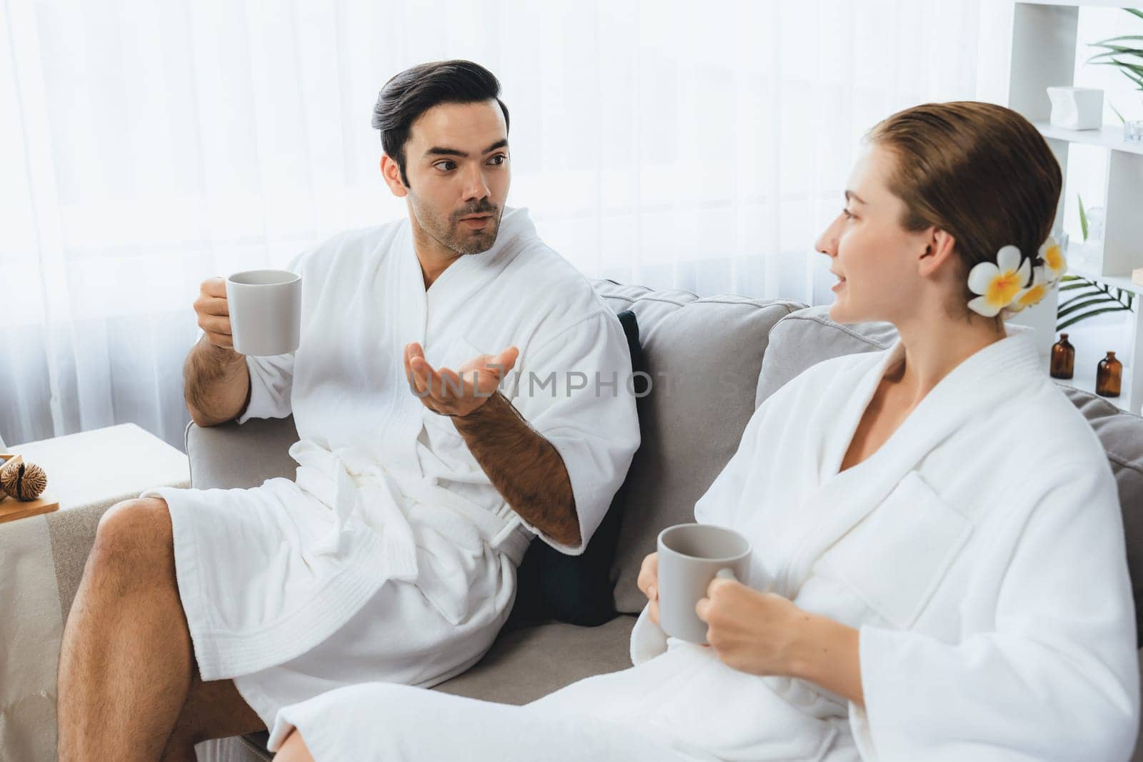 Beauty or body treatment spa salon vacation lifestyle concept with couple wearing bathrobe relaxing with drinks in luxurious hotel spa or resort room. Vacation and leisure relaxation. Quiescent