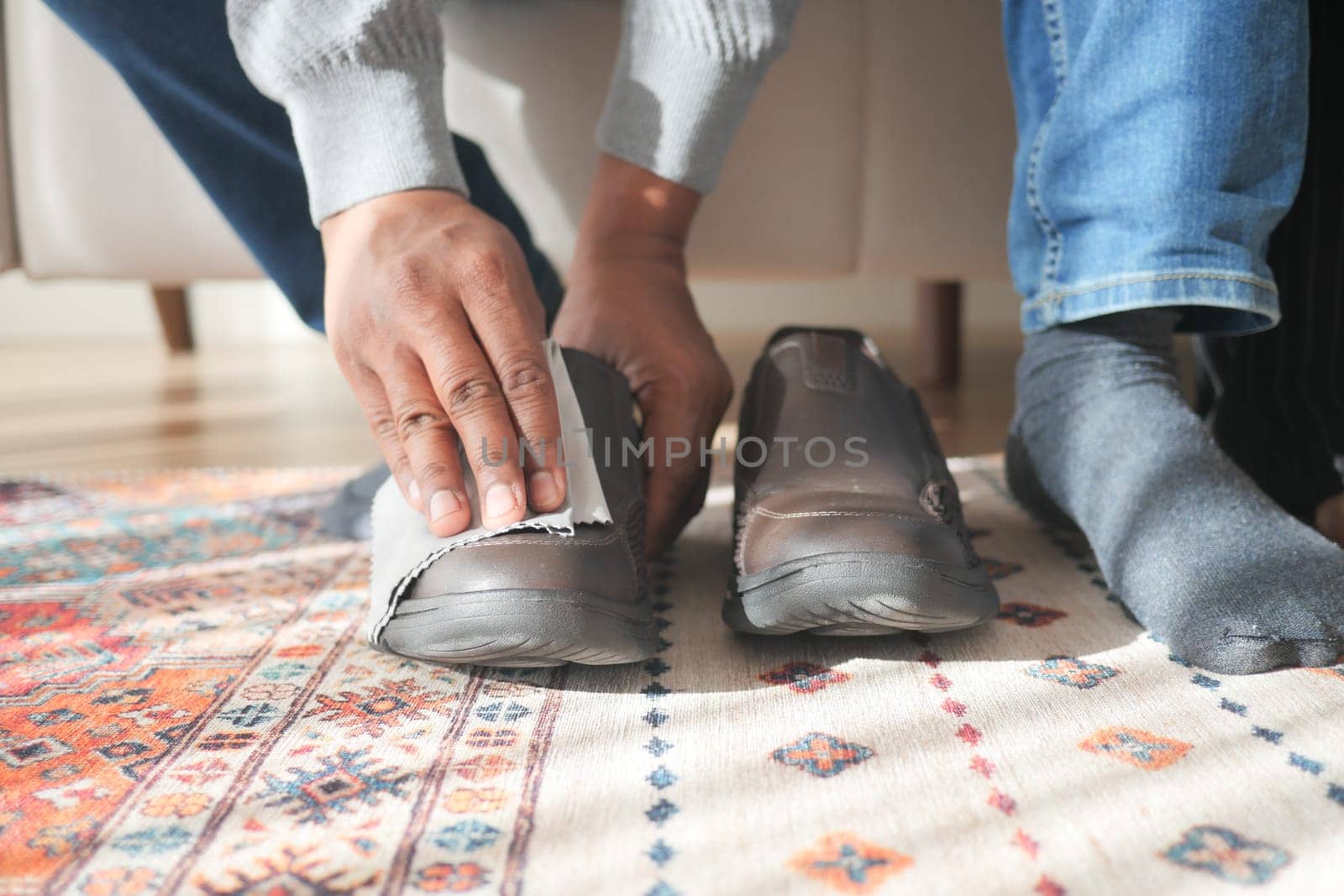 man wipes his leather shoes with a wet cloth.