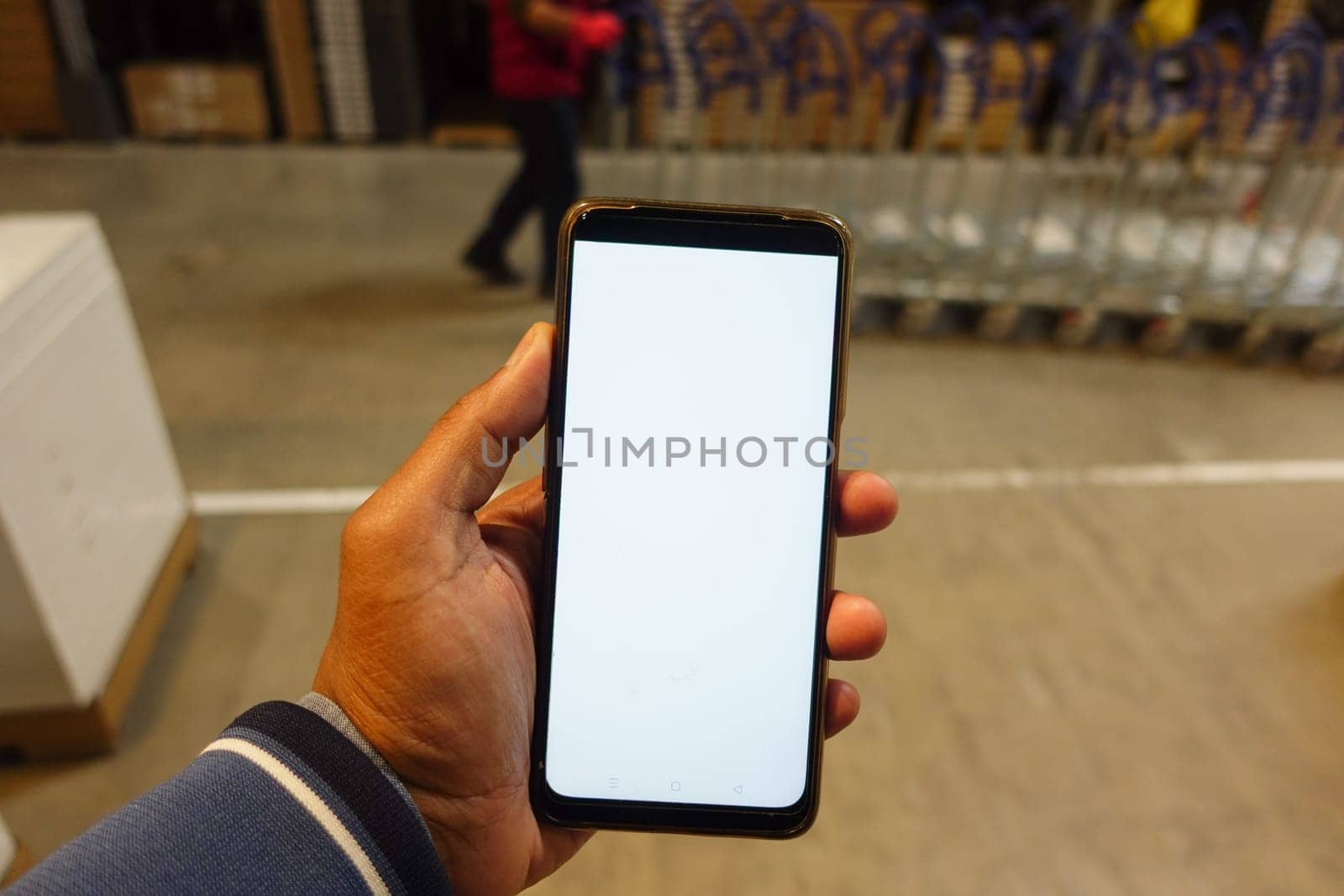 business owner holding phone mock up in warehouse