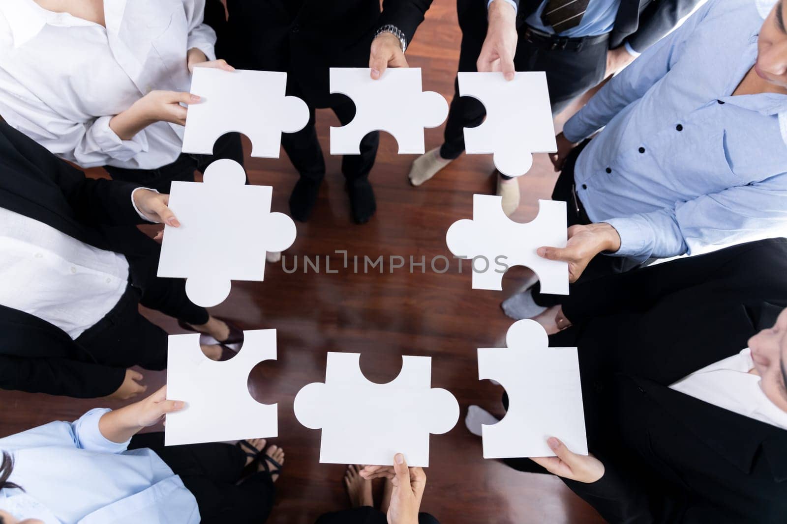 Top view multiethnic business people holding jigsaw pieces and merge them together as effective solution solving teamwork, shared vision and common goal combining diverse talent. Meticulous