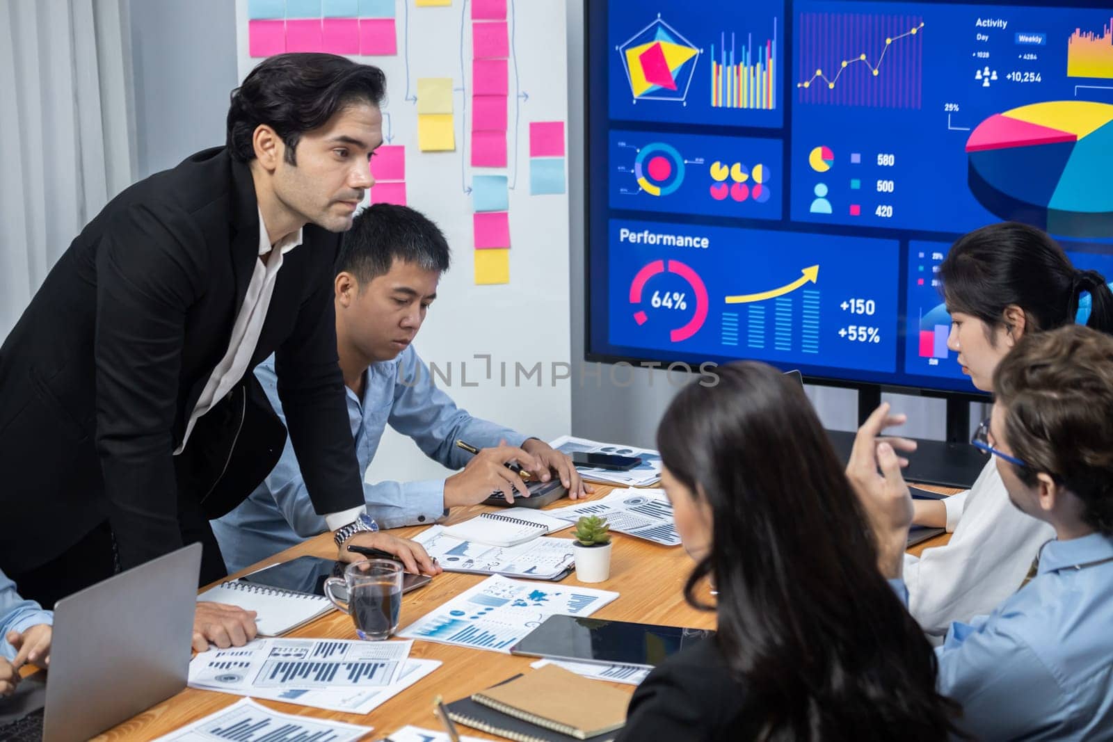 Wide top view of diverse group of business analyst team analyzing financial data report paper on meeting table. Chart and graph dashboard by business intelligence analysis. Meticulous