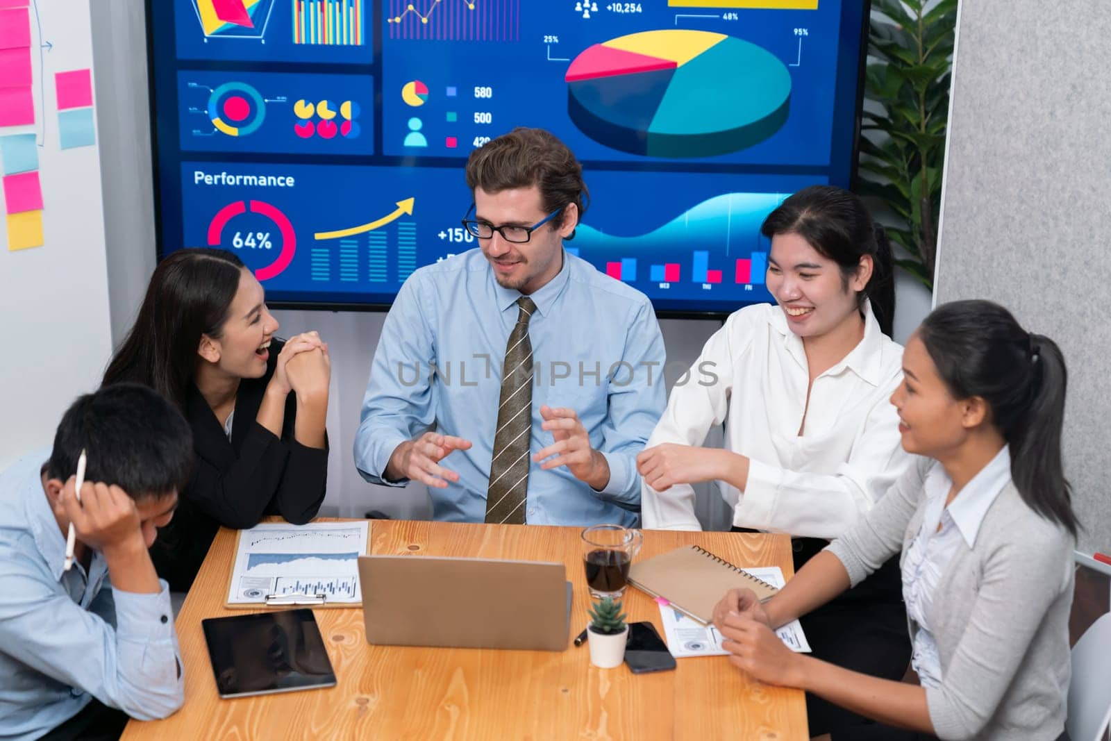 Diverse group of business analyst team analyzing financial data report. Finance data analysis chart and graph dashboard show on TV screen in meeting room for strategic marketing planning. Meticulous