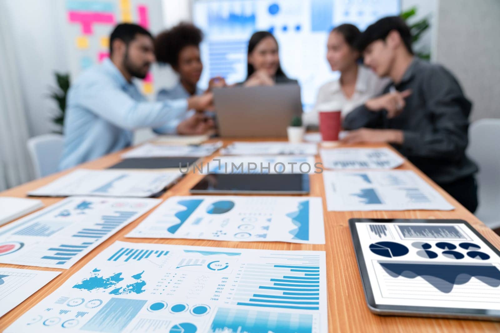 Focus financial dashboard paper showing graphs and chart with blurred background of diverse business people analyzing business data by BI Fintech technology for business marketing indication. Concord