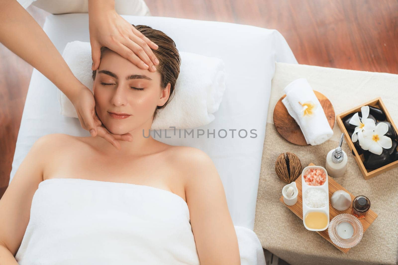 Caucasian woman enjoying relaxing anti-stress head massage and pampering facial beauty skin recreation leisure in dayspa modern light ambient at luxury resort or hotel spa salon. Quiescent