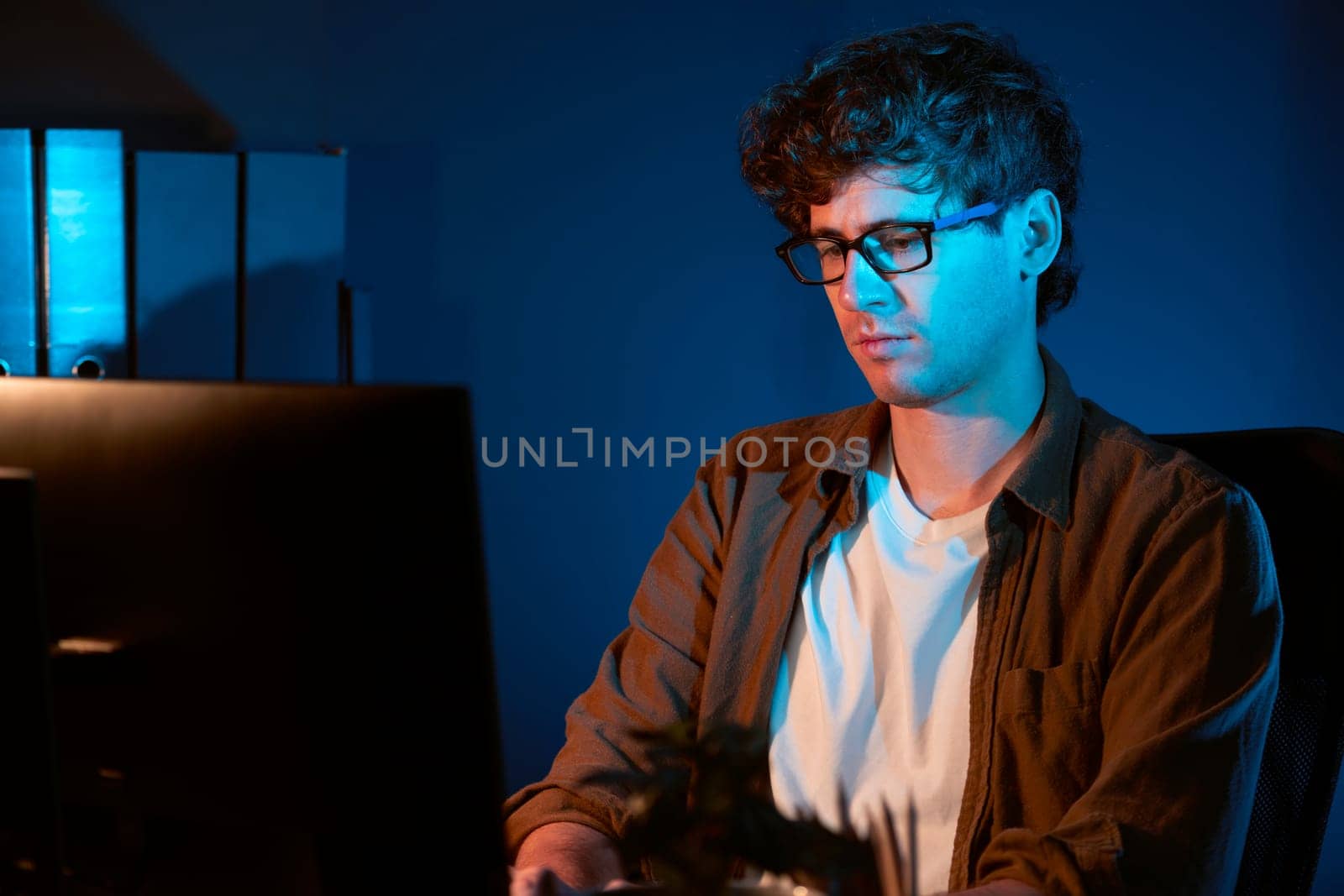 Young businessman concentrating on pc for creative startup project job at neon light modern office. Thinking marketing network online planning of creator to market channel design concept. Gusher.
