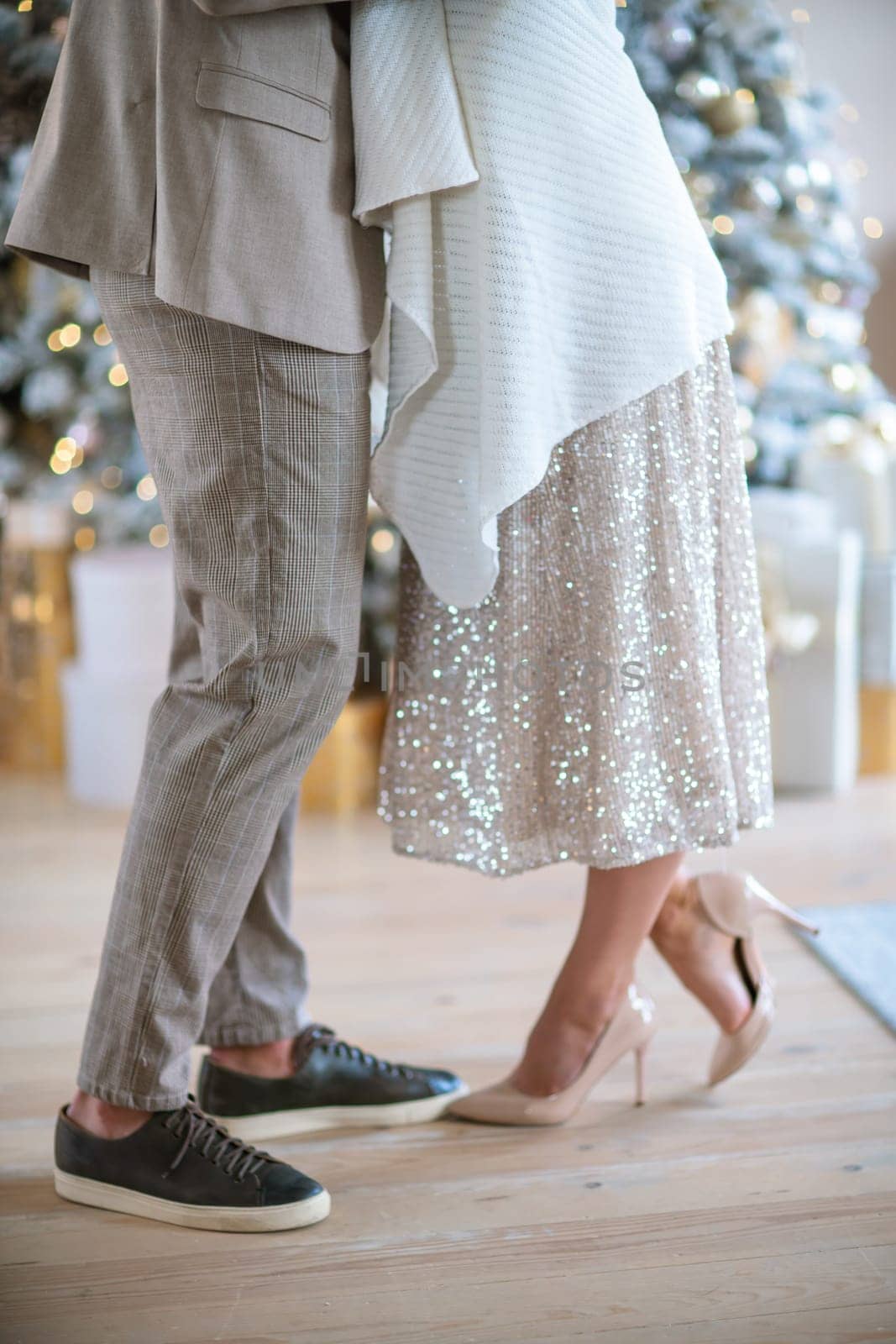 Romantic couple standing near Christmas tree at home and hugging.