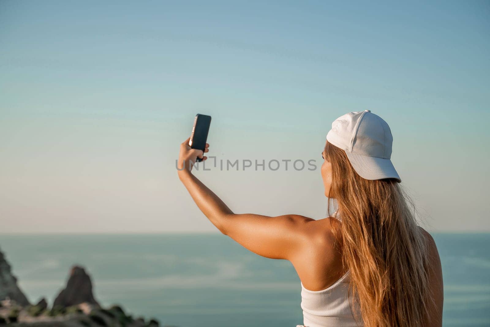 Selfie woman in cap and tank top making selfie shot mobile phone post photo social network outdoors on sea background beach people vacation lifestyle travel concept