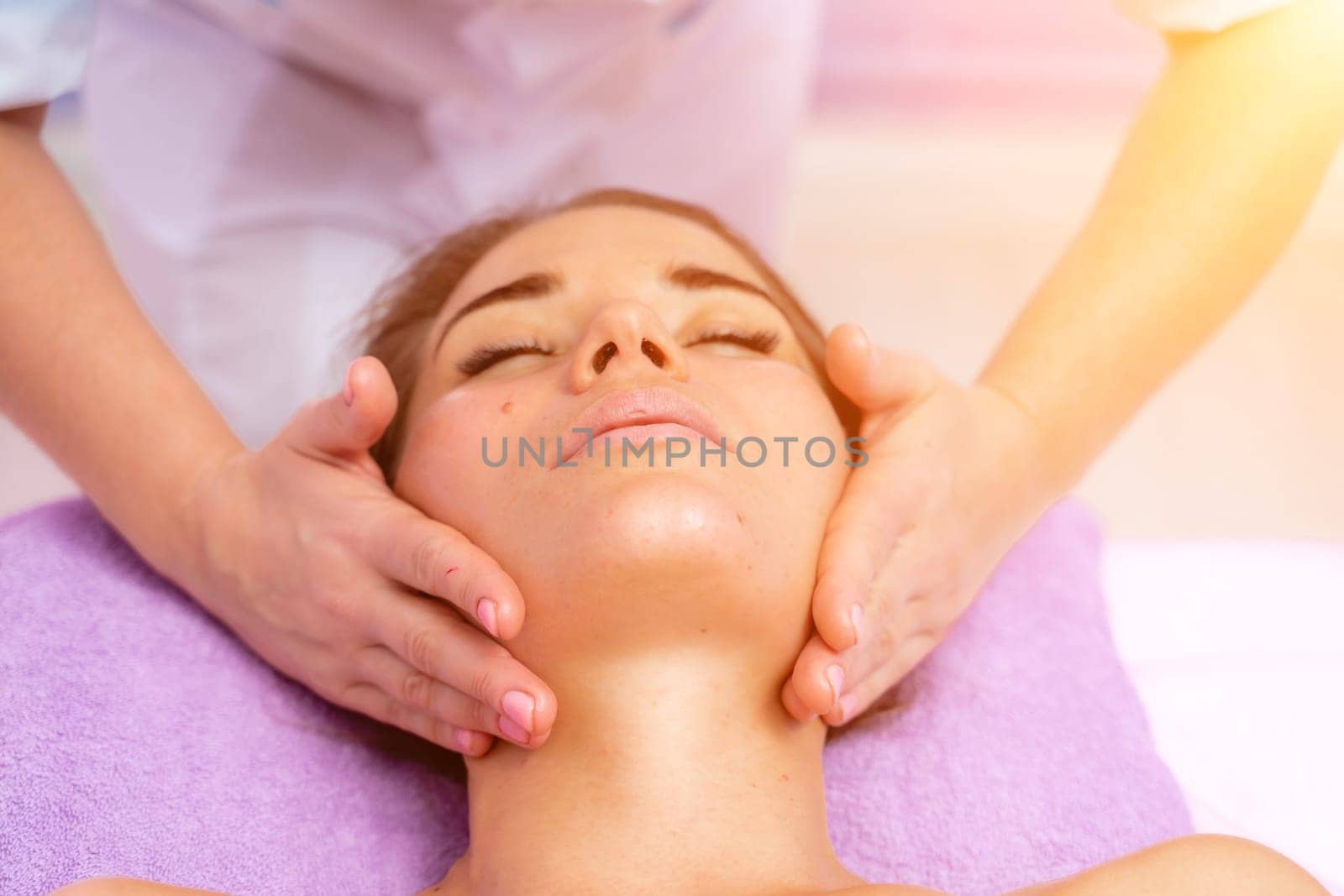 Relaxing massage. European woman getting facial massage in spa salon, side view.