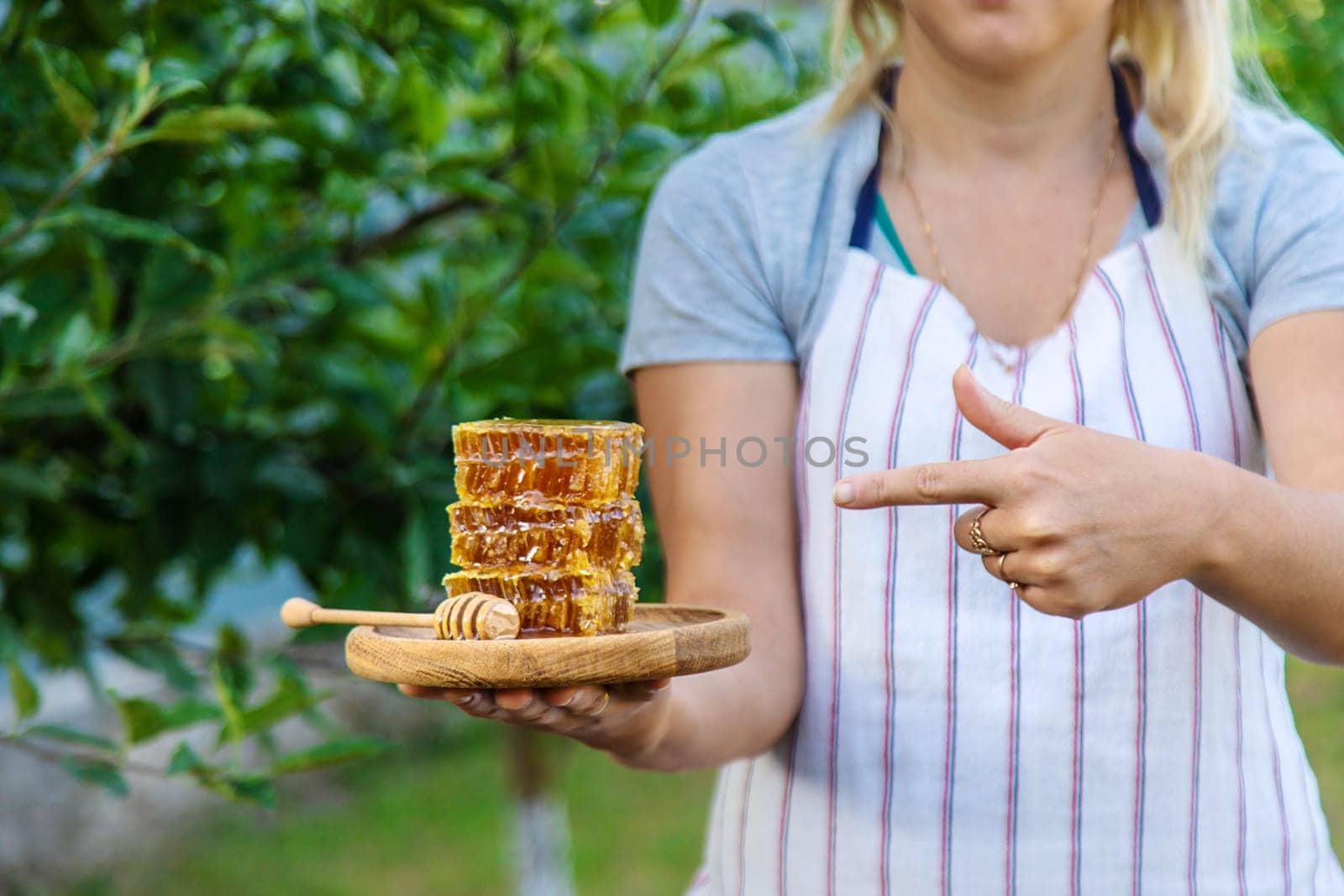 A woman holds honey in the garden. Selective focus. Nature.