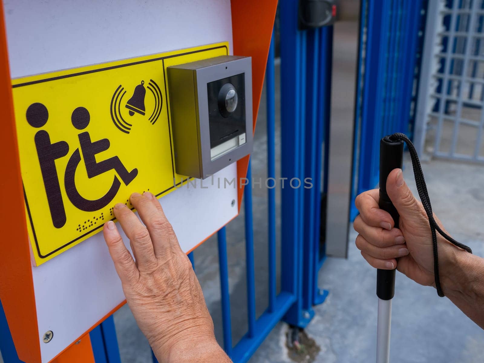 Close-up of the hands of a blind elderly woman reading a text in braille. Button for calling help for people with disabilities