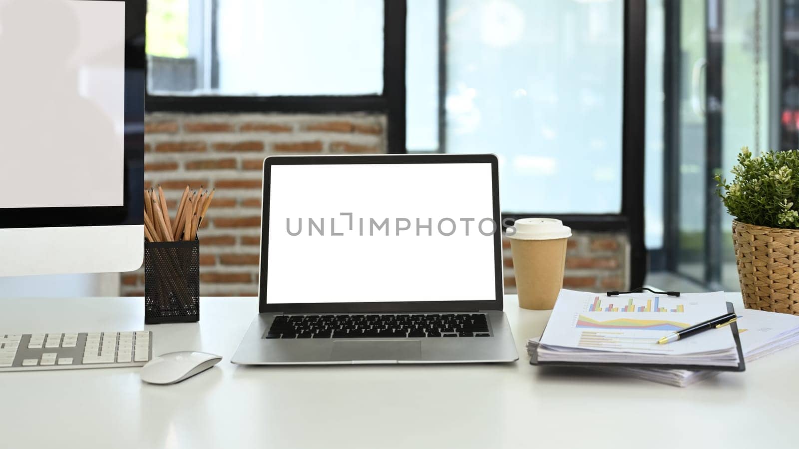 Front view laptop, financial document, coffee cup and stationery on white table.