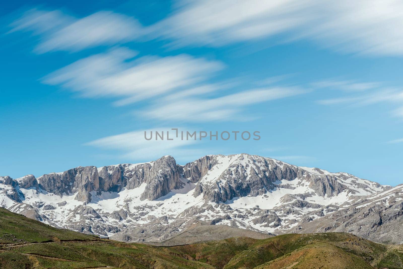 The lush green Sobucimen plateau in spring and the mountains with some melted snow behind.